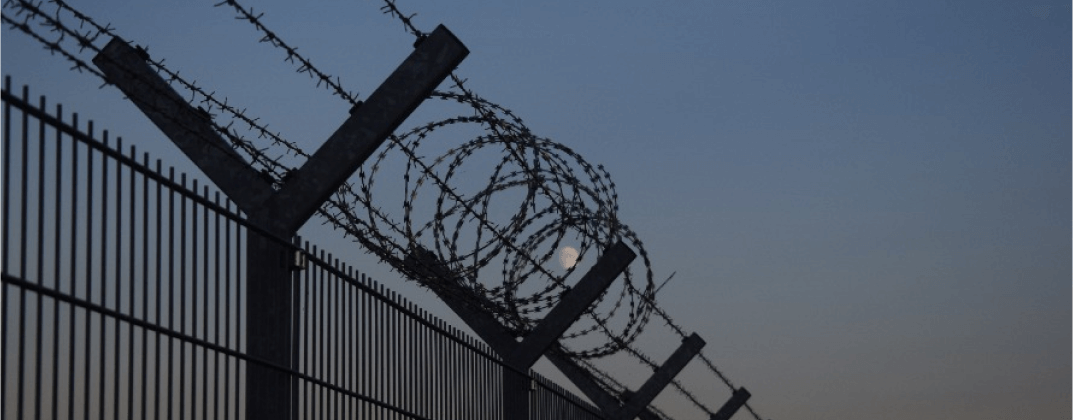 A metal fence with barbed wire