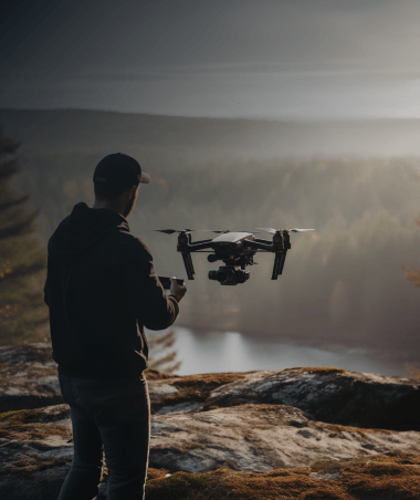A man operates a drone in the forest